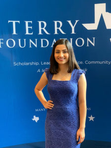Terry Scholar in a formal blue dress, standing in front of a Terry Foundation backdrop.