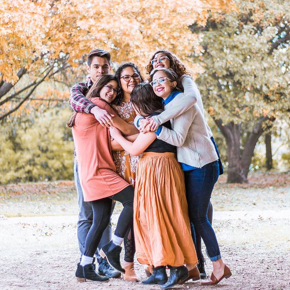 Terry Scholar, Olivia Arratia, with her 5 siblings outdoors. All are hugging and smiling.